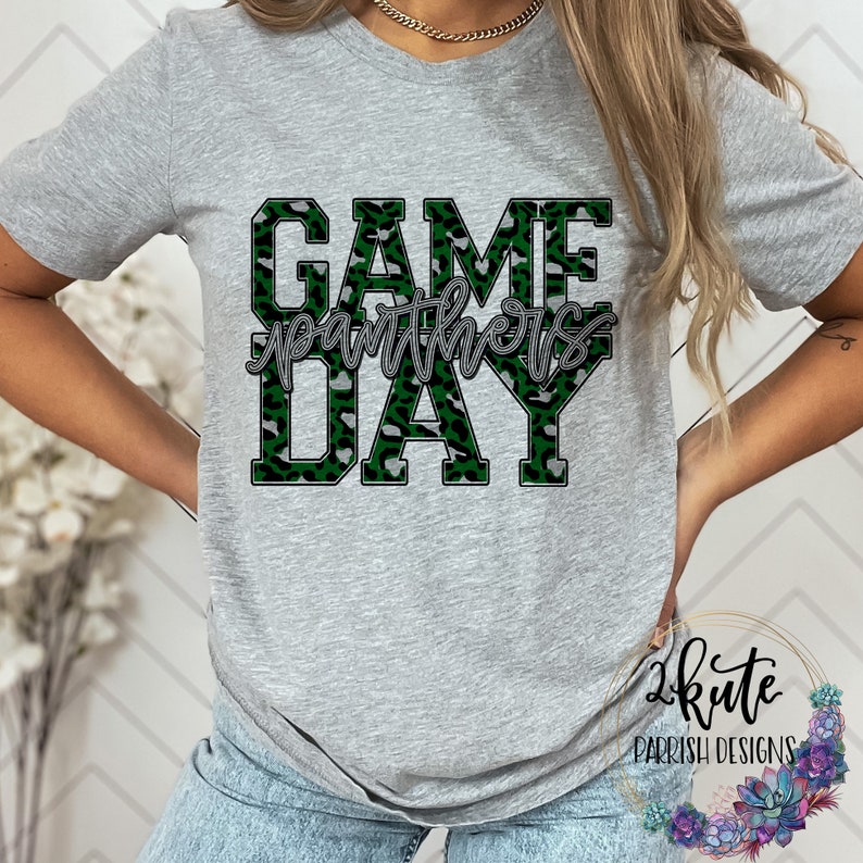 May include: Gray t-shirt with a green and gray leopard print design that says "GAME DAY" with the word "Panthers" written in cursive underneath.
