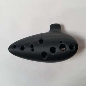 May include: A black ocarina with multiple finger holes. The ocarina is a wind instrument.