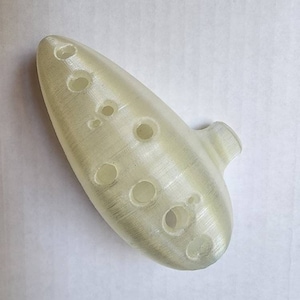 May include: A white ocarina with eight finger holes. The ocarina is made of a smooth, white plastic and has a slightly textured surface.