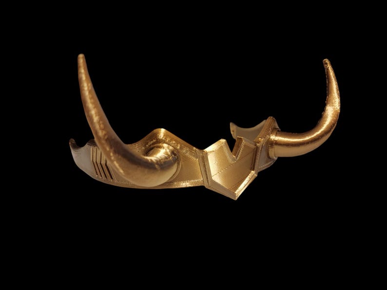 May include: A gold-colored crown with two horns, resembling a crown worn by a mythical creature.