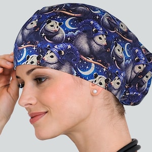 May include: A dark blue surgical scrub cap featuring a repeating pattern of opossums wearing wizard hats, moons, and stars. The cap is made of a soft fabric and is designed to be worn in a medical setting.
