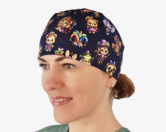 May include: A navy blue surgical scrub cap featuring colorful cartoon animals in Mardi Gras attire. The cap is patterned with bears, monkeys, frogs, and pugs wearing festive costumes. The cap is worn by a person.