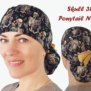 Puede incluir: Un gorro de quir&oacute;fano negro para coleta con un patr&oacute;n repetido de esqueletos y elementos florales. El gorro tiene un lazo dorado en la parte trasera. El texto "Skull 31 Ponytail New" es visible.