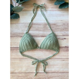 May include: A sage green crocheted bikini top with adjustable straps. The top is tied at the neck and back.