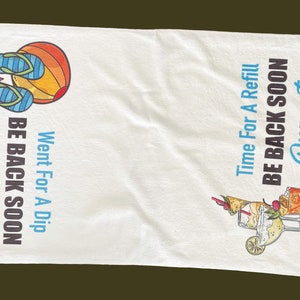 May include: White beach towel with colorful illustrations of flip-flops, a sunset, and cocktails. Text reads "Went For A Dip, Be Back Soon, Durant" and "Time For A Refill, Be Back Soon, Durant."