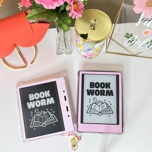 May include: Two pink and clear plastic e-reader cases with the text "BOOK WORM" and a cartoon worm on a book.