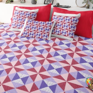 May include: A bed set featuring a geometric pattern in shades of red, purple, and pink. The set includes a patterned bedspread, two patterned pillows, and two solid red pillows. The design is a repeating triangle pattern.