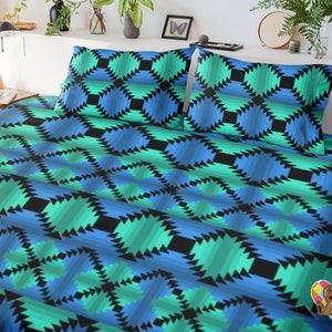 Puede incluir: Un juego de cama con estampado geométrico azul y verde con dos fundas de almohada. El patrón está formado por formas repetidas que se asemejan a una serie de triángulos.