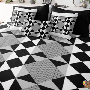 May include: Black and white geometric patterned bedding with a black and white geometric patterned pillow. The bedding has a black and white checkered pattern with a gray stripe.