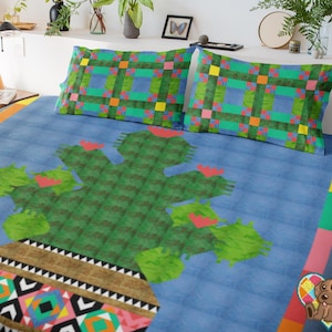 May include: A blue and green patterned bedspread with a cactus design in the center. The cactus is green and has pink flowers. The bedspread has a colorful border with a geometric pattern.