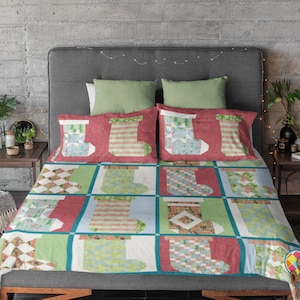 May include: A red, green, and blue Christmas quilt with a stocking pattern. The quilt is on a bed with green and white pillows.