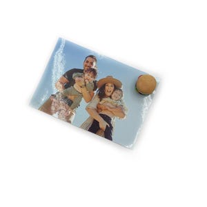 Peut inclure: Une planche &agrave; d&eacute;couper rectangulaire en verre avec une photo de famille et un accessoire de burger. La photo montre une famille de quatre personnes souriantes. Le burger a un pain, un steak, de la laitue et une tomate. Le fond est blanc.