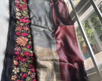 Pode incluir: Um sari de seda preto com uma borda vinho e bordados florais intrincados em tons de rosa, verde e branco.