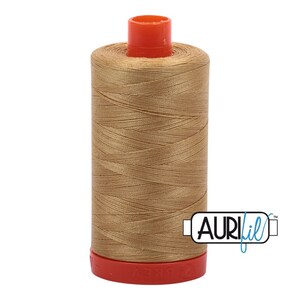 Può includere: Un'bobina di filo Aurifil di colore marrone chiaro. La bobina è etichettata con il logo Aurifil in blu e bianco.