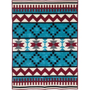 Puede incluir: Una colcha con un patrón geométrico en tonos de rojo, blanco, negro y azul. El patrón presenta zigzags, cuadrados y triángulos.