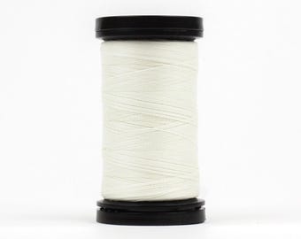 May include: A spool of white thread with a black plastic cap on each end.