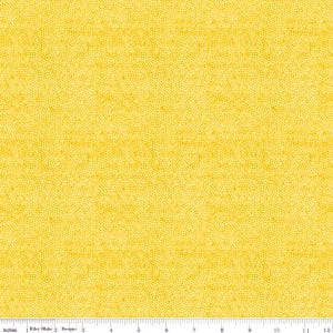 Puede incluir: Tela de color amarillo brillante con un patrón moteado. La tela tiene una textura y un color uniformes, con pequeños puntos espaciados uniformemente en la superficie. La imagen incluye una regla con pulgadas.