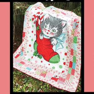 May include: A white, red, and green patchwork quilt with a cute cartoon kitten in a stocking. The quilt is titled "Whiskers" and is by Tricia Lynn Maloney for Villa Rosa Designs.