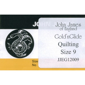 Könnte beinhalten: Ein weißes Etikett mit schwarzem Text, der "John James of England Gold'nGlide Quilting Size 9 JJEG12009" lautet. Das Etikett hat ein Schwarzweißbild eines Drachen im Hintergrund.