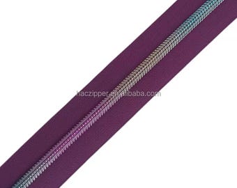 Op de afbeelding: Een close-up van een paarse ritsband met een regenboogkleurige, iriserende ritssluiting. De ritsband is glad en de ritssluiting is van metaal.