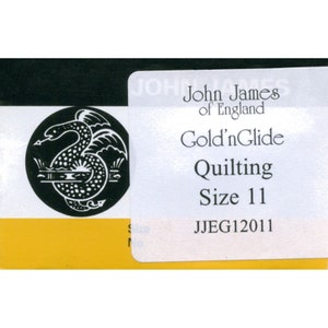 May include: A white label with black text reads "John James of England Gold'nGlide Quilting Size 11 JJEG12011". A black and white illustration of a dragon is in the background.