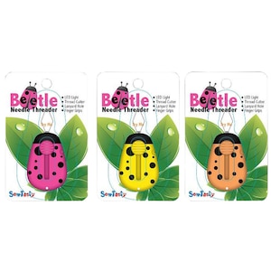 May include: Three beetle-shaped needle threaders in pink, yellow, and orange. Each has black spots, a thread cutter, and finger grips. The packaging includes the text "Beetle Needle Threader" and "SewTasty".