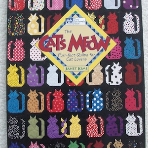 May include: A book titled The Cat's Meow: Purr-fect Quilts for Cat Lovers by Janet Kime. The cover features a black background with a grid of colorful, patterned cat-shaped quilt blocks in various colors including red, blue, yellow, and purple.