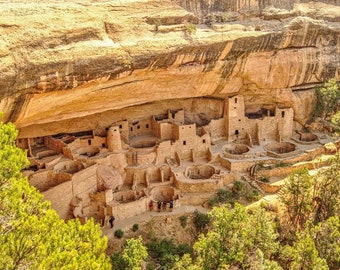 Pode incluir: Uma vista aérea de uma habitação em um penhasco em um cânion. A habitação é feita de pedra e tem muitos quartos e níveis. A habitação está localizada em uma área remota e é cercada por árvores e rochas.