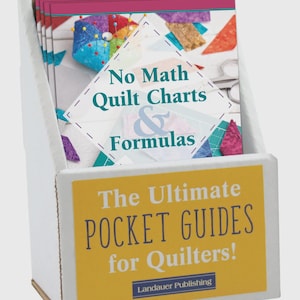 May include: A white cardboard display box filled with several "No Math Quilt Charts & Formulas" books. The books have colorful quilt block images and are labeled "The Ultimate Pocket Guides for Quilters!" by Landauer Publishing.