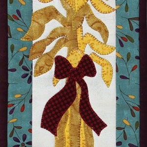 May include: A fall-themed fabric wall hanging. It features a central design of a corn stalk with a burgundy bow, pumpkins, and a basket filled with corn and gourds. The background is teal with floral and leaf patterns.