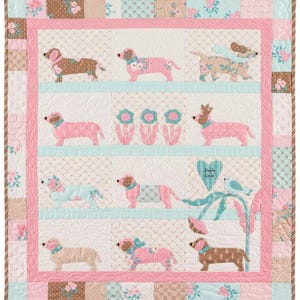 May include: A pink and brown patchwork quilt with a whimsical design featuring a variety of dachshund dogs in different poses. The quilt has a pink and brown border and the text "Dixie Love" in a heart shape.