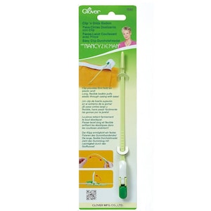 May include: Green and white plastic tool with a long, flexible needle for threading elastic through casings. The tool is labeled "Clip 'n Glide Bodkin" and "Easy Clip-Durchziehnadel" with the name "NANCYZIEMAN" printed on the packaging.