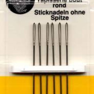 May include: Package of six tapestry needles, size 22, by John James. The needles are blunt and made in England. The package is yellow and white with the John James logo and text in black.