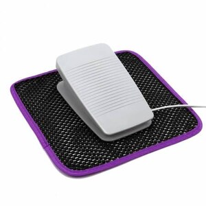 May include: A white foot pedal with a black mesh mat with a purple border. The pedal has a cord attached to it.