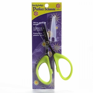Puede incluir: Tijeras pequeñas de color verde y plateado con una cubierta protectora de plástico. El embalaje dice "Karan Kay Banking's Perfect Scissors SMALL" y "Micro serrated blade, Comfortable soft handle, Protective plastic cover."