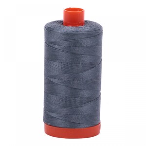 Puede incluir: Una bobina de hilo gris con una bobina de plástico naranja.