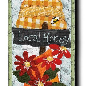 May include: A green and white quilted wall hanging featuring a beehive, flowers, and a sign that reads "Local Honey". The top of the hanging has a black metal sign that says "Blessed".