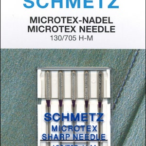 Puede incluir: Un paquete de seis agujas de máquina de coser plateadas en una caja de plástico transparente. Las agujas están etiquetadas como "Schmetz Microtex Sharp Needle 130/705 H-M". El paquete también incluye una tabla de tallas con los tamaños de aguja 60, 70 y 80.
