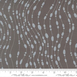 May include: A fabric featuring a repeating pattern of pale blue ovals and circles linked by white lines on a brown backdrop. The design has a flowing, organic feel, with the lines curving across the fabric. The fabric is marked with a ruler.