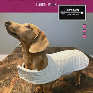 May include: A dachshund wearing a light gray quilted jacket. The image includes text that reads "THE DANDY-DOO TOTALLY REVERSIBLE, TOTALLY ADJUSTABLE JACKET PATTERN FOR MEDIUM & LARGE DOGS" and "QUILTED JACKET PATTERN FOR YOUR BEST FRIEND."
