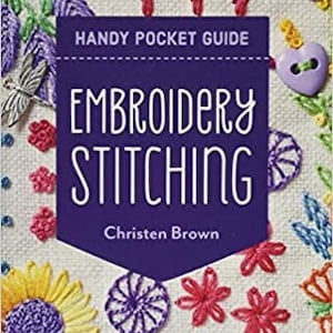 Peut inclure: Un livre violet intitulé "Embroidery Stitching: Handy Pocket Guide" par Christen Brown. La couverture présente des points de broderie colorés et le texte "30+ Stitches | All the Basics & Beyond".