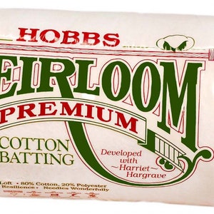 May include: A package of Hobbs Heirloom Premium Cotton Batting. The white batting is wrapped in clear plastic. The packaging features the words "Heirloom Premium Cotton Batting" in green and red lettering.
