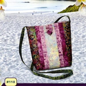 May include: A colorful, patterned Carmel Swing Bag with a button closure and a green strap. The bag is made with 2 1/2" strips and includes color picture instructions. The text "Pink Sand Beach Designs" is at the top.