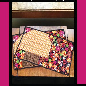 May include: Two quilted placemats with a mushroom theme. The placemats are made of fabric with a floral pattern and a honeycomb pattern. The placemats are on a wooden table. The text "LITTLE 'SHROOM SNACK MAT" is at the top of the image. The text "Tricia Lynn Maloney Orphan Quilt Designs for Villa Rosa Designs" is at the bottom of the image.