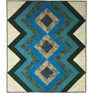 May include: A handmade quilt with a geometric design. The quilt features a central pattern of diamonds and zigzags in shades of blue, teal, and tan, with a cream-colored border. The quilt is machine-stitched.