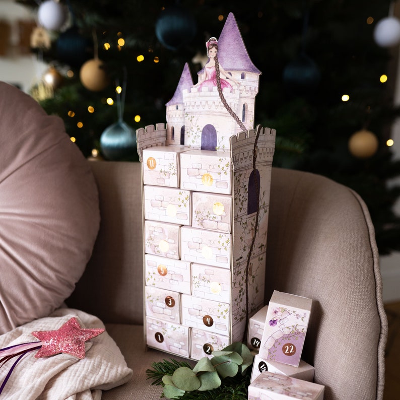 Der Adventskalender steht aufgebaut auf einem Sofa. Der Turm wird auf einfache Weise zusammengesteckt ohne Kleber.  Ein origineller Adventskalender zum Selberbasteln und Befüllen, tolle Adventsidee 2024.