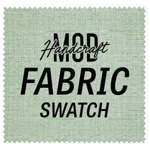 May include: A square fabric swatch with a light green textured surface and a decorative zig-zag edge. The words "MOD Handcraft FABRIC SWATCH" are printed in black, with "Handcraft" in a cursive font.