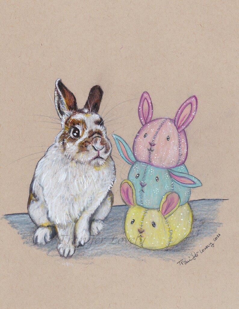 May include: A white and brown rabbit sits next to a stack of three handmade fabric bunny toys. The toys are pink, blue, and yellow with white stitching. The toys are stacked on top of each other.