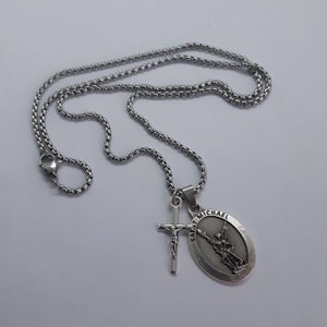 K&ouml;nnte beinhalten: Eine silberfarbene Halskette mit einer Kette und zwei Anh&auml;ngern. Ein Anh&auml;nger ist ein Kreuz mit einer Jesusfigur, der andere ein ovaler Anh&auml;nger mit den Worten "SAINT MICHAEL" und einem Engelbild.