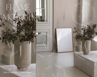May include: A white frame mockup with a light wood frame, sitting on a white tiled floor. The frame is placed in front of a white wall with a white door to the left. A vase with dried flowers is on a white tiled surface to the left of the frame. The text "FRAME MOCKUP" is at the top of the image.